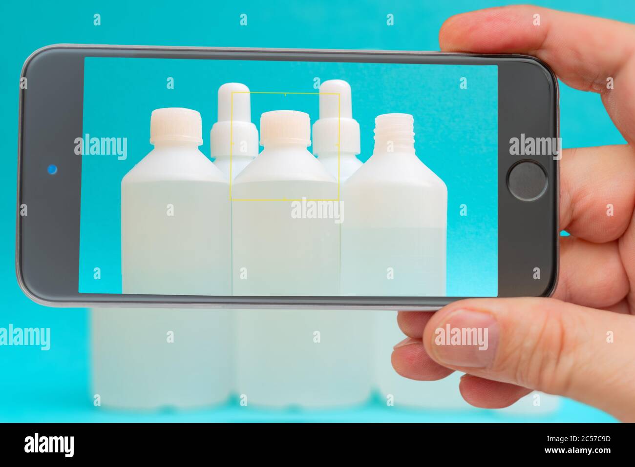 Flacons antiseptiques sur l'écran du smartphone. Liquide désinfectant dans une bouteille blanche. Médicament thérapeutique. Désinfection contre le coronavirus. Banque D'Images