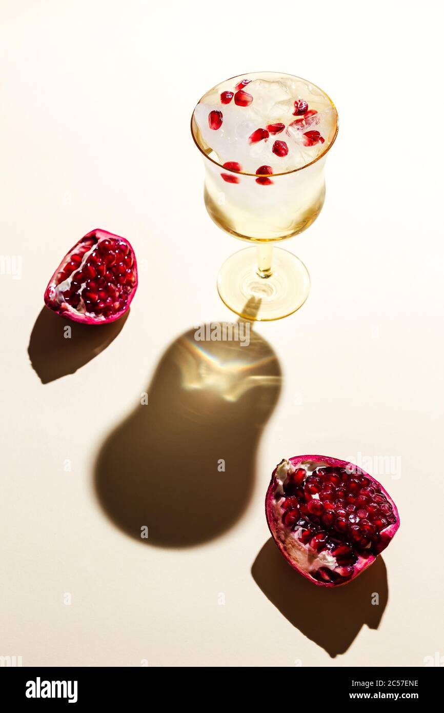 Un beau verre d'eau tonique glacée avec grenade, dos dur, ombres profondes Banque D'Images