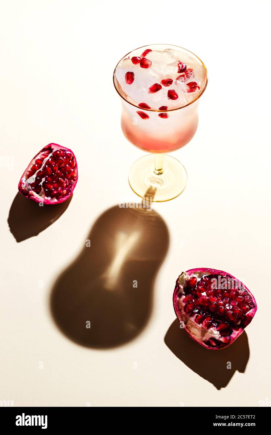 Un beau verre d'eau tonique glacée avec grenade, dos dur, ombres profondes Banque D'Images