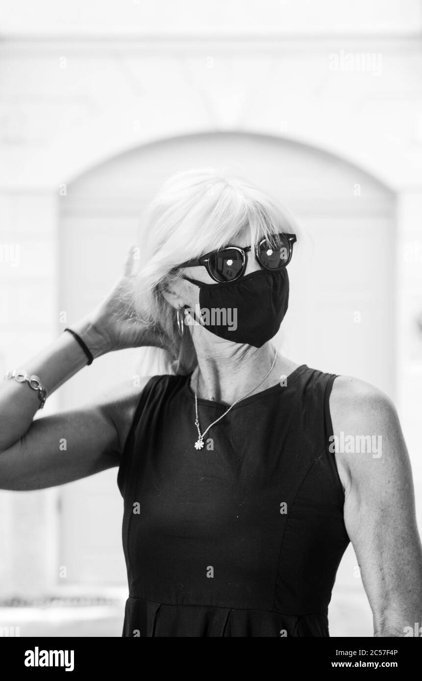 Portrait de la femme belle 50s 60s adulte mature caucasien européen blond cheveux dame portant un masque de protection chirurgical et sombre habillé. Banque D'Images
