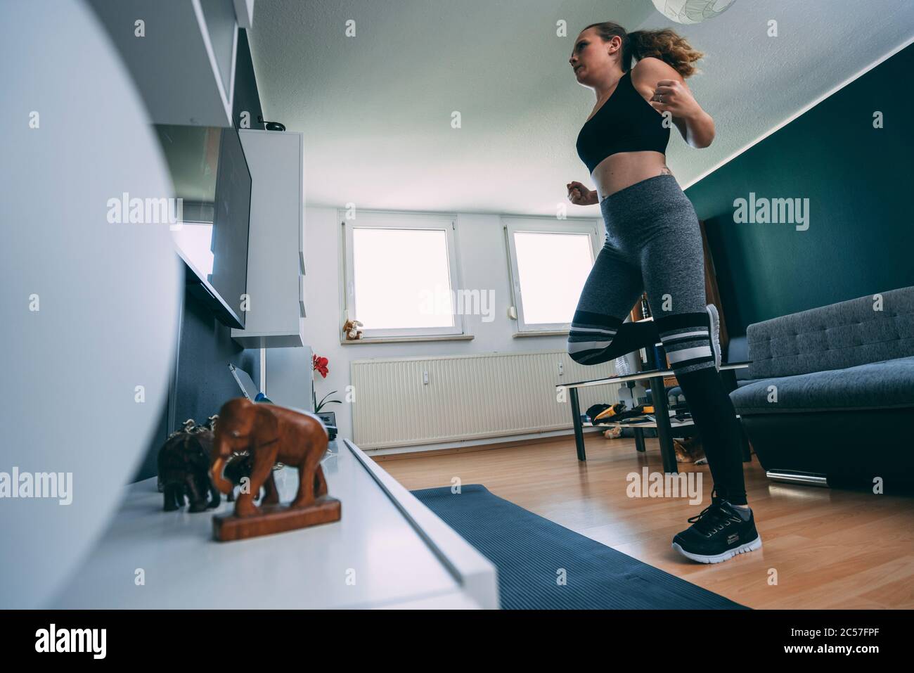 Europe, Allemagne, Rosenheim, Jeune Femme fait de l'entraînement sportif à domicile, Livingroom Banque D'Images