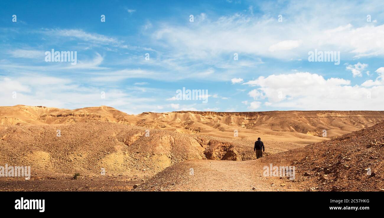 un seul randonneur solitaire sur le sentier vers le canyon rouge dans les montagnes eilat d'israël avec des caractéristiques géologiques et un ciel spectaculaire Banque D'Images