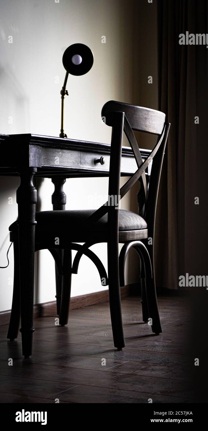 Plan vertical d'une chaise en bois et d'une table avec une lampe s'allume Banque D'Images