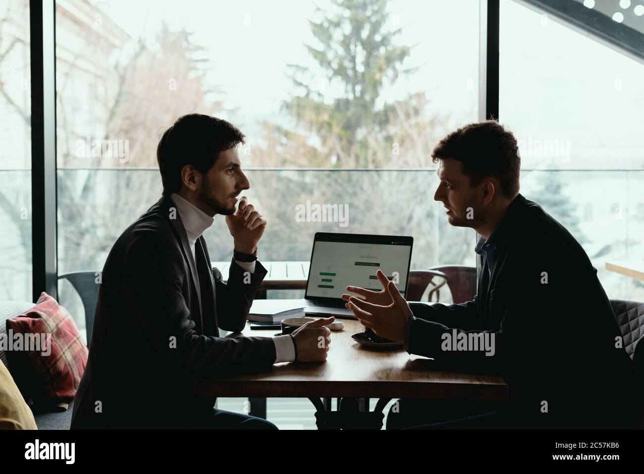 Deux hommes d'affaires parlent de nouvelles opportunités assis avec un ordinateur portable au bureau, projet de planification, considérant l'offre d'affaires, partager des idées Banque D'Images