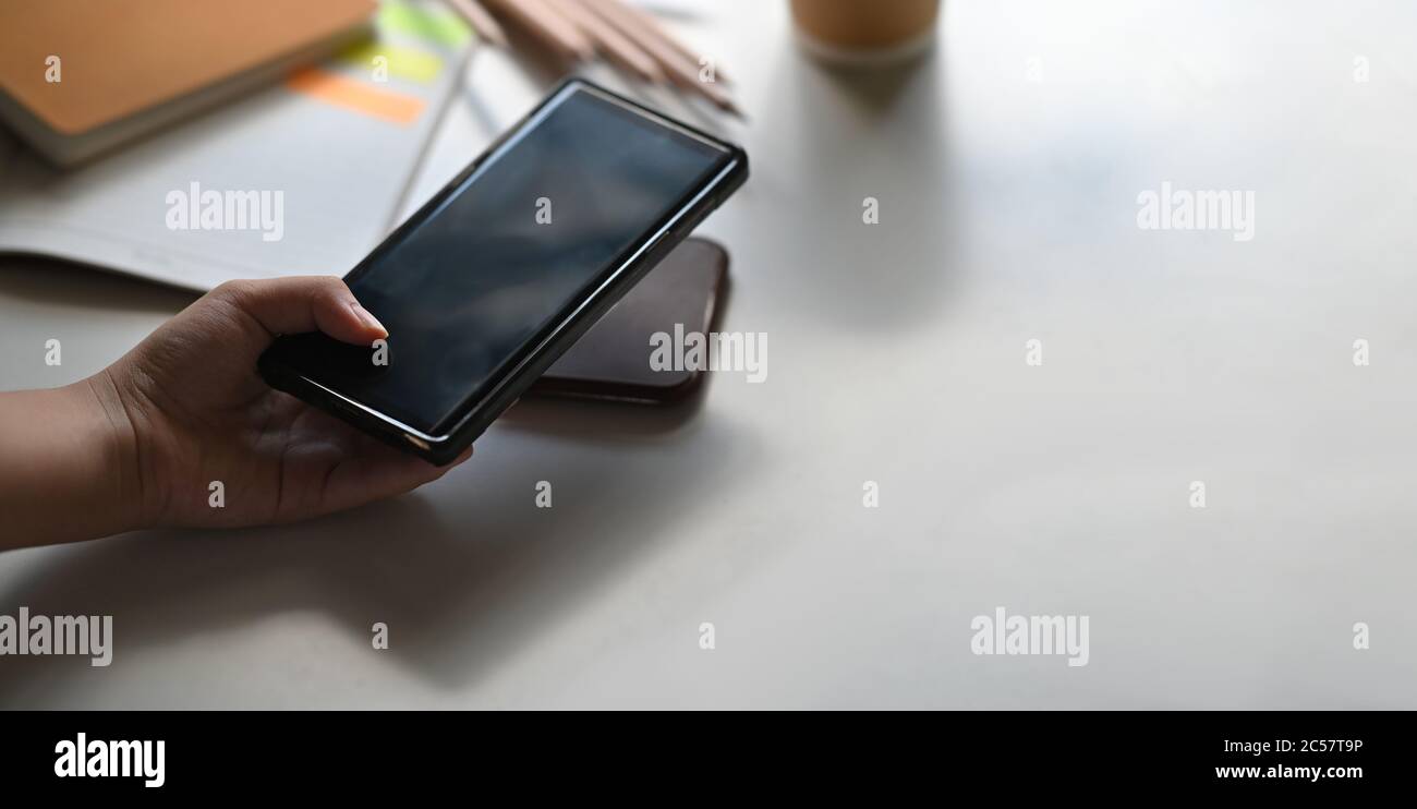 Une main est de placer un téléphone mobile sur un chargeur sans fil au-dessus de la table comme un arrière-plan. Banque D'Images