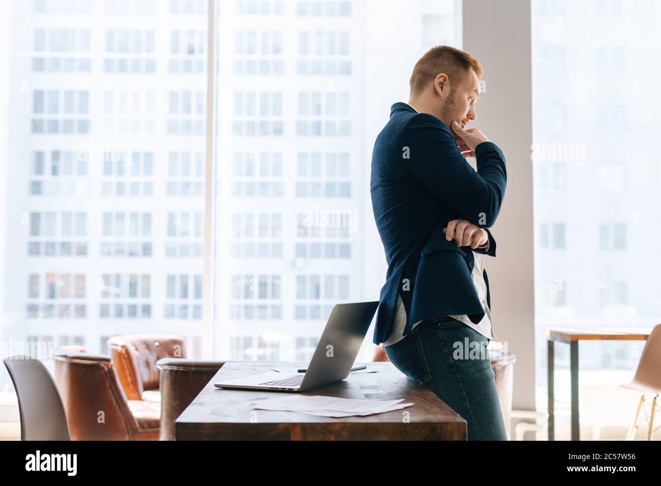 Vue latérale d'un jeune homme d'affaires attentionné portant des vêtements de costume dans une salle de bureau moderne Banque D'Images