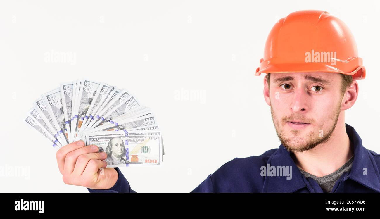 Le constructeur gagne de l'argent, le réparateur conserve de l'argent, le ventilateur fait de billets en main. L'homme en casque a obtenu un salaire, de l'argent pour le travail. Beau-homme avec un visage strict dans un casque sur fond blanc. Concept immobilier. Banque D'Images