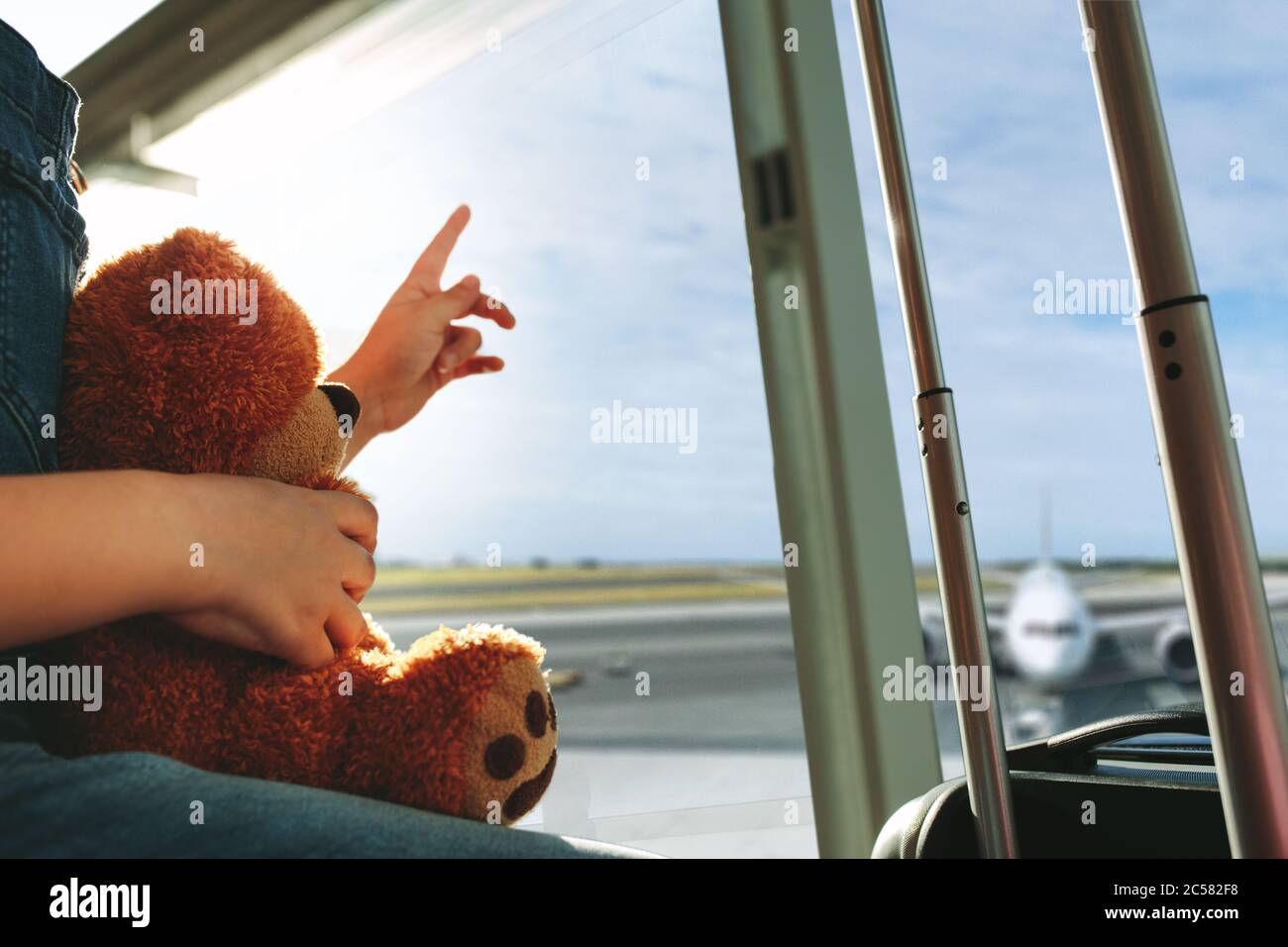 Photo rognée d'un doigt d'homme pointant vers le ciel et montrant l'avion à sa fille en attendant au terminal de l'aéroport. Famille assise près d'un W Banque D'Images