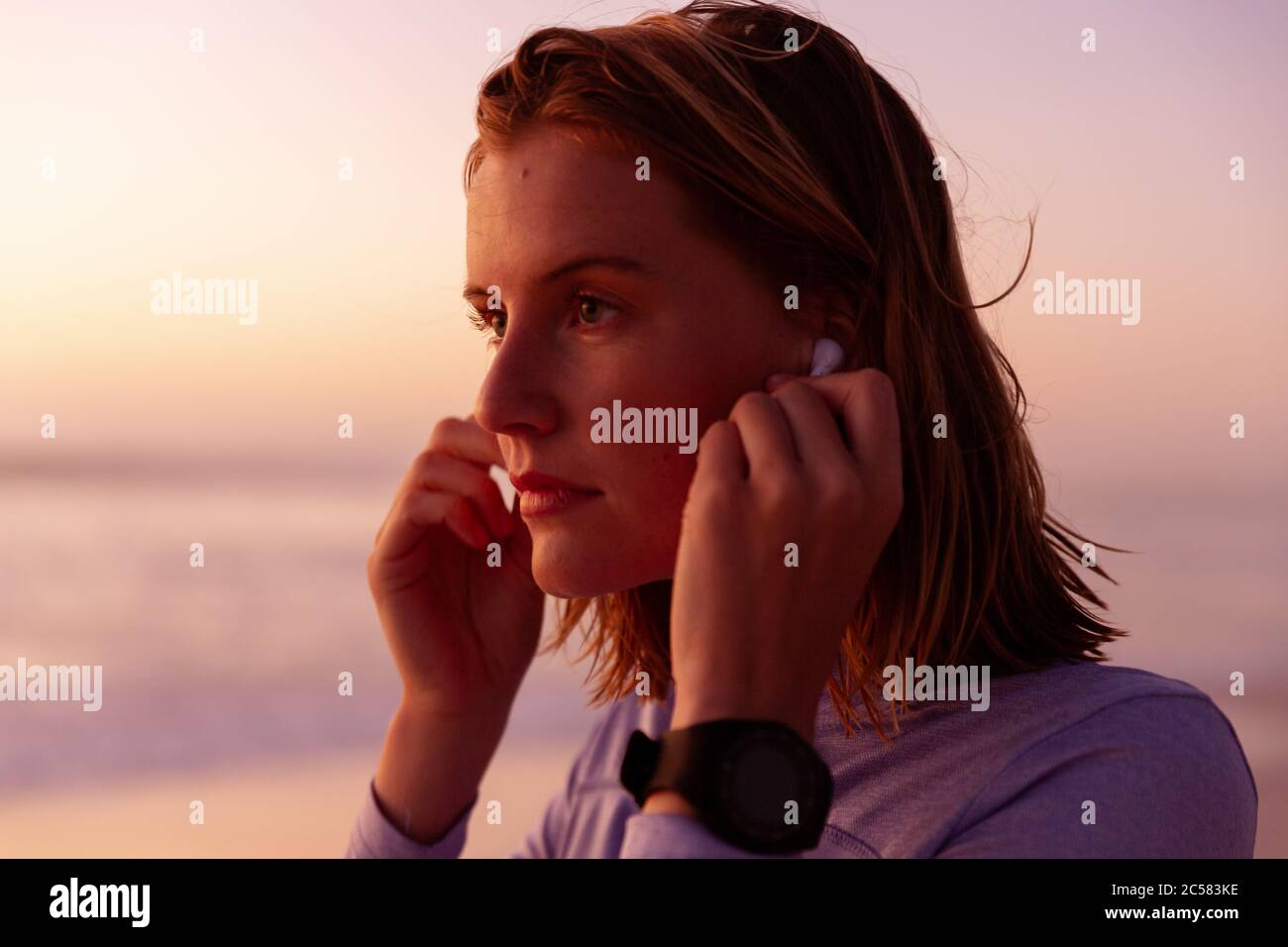 Belle femme portant des écouteurs sur la plage Banque D'Images