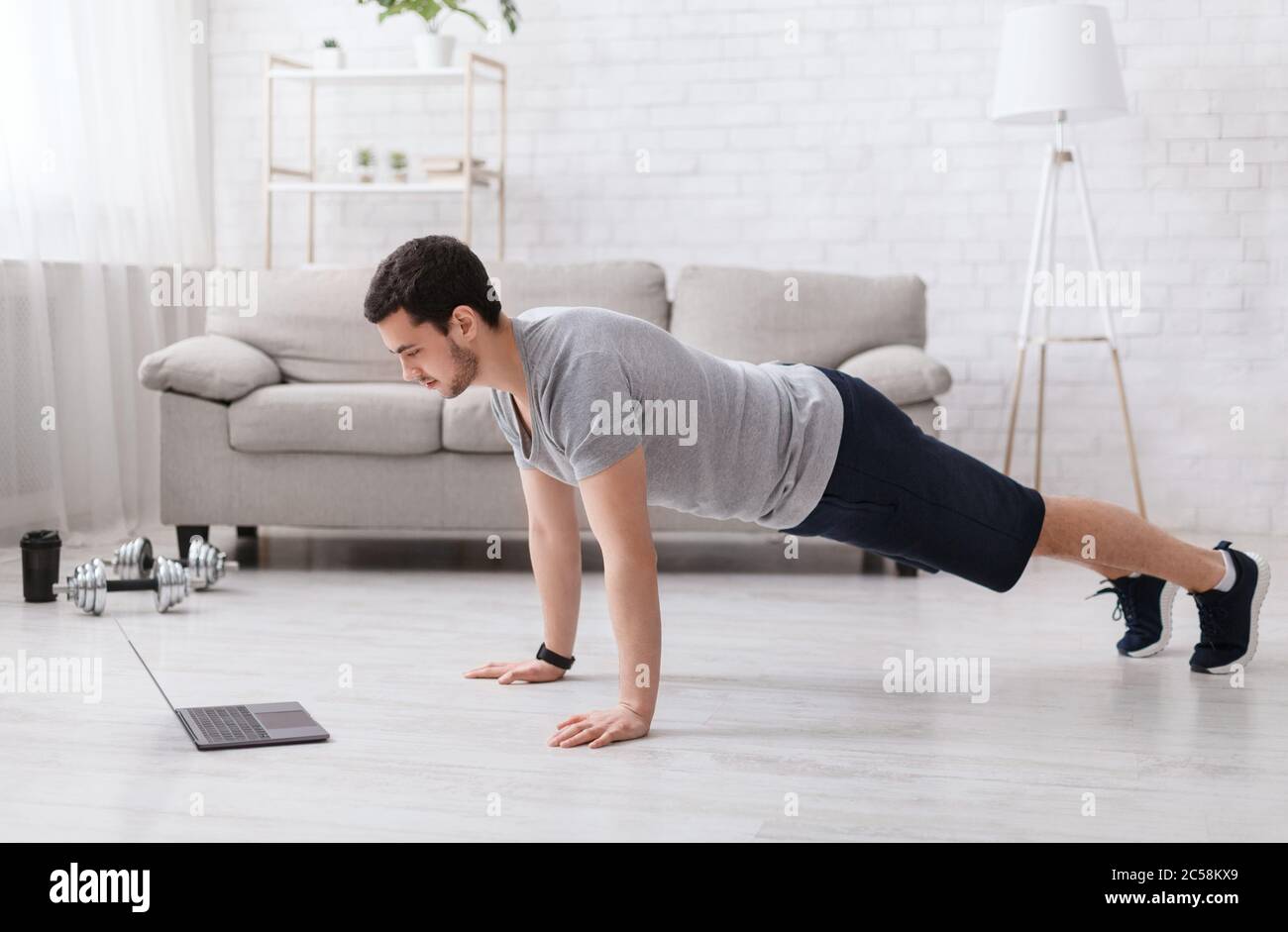 Soins du corps et sports. Guy fait des push-up et regarde l'ordinateur portable Banque D'Images