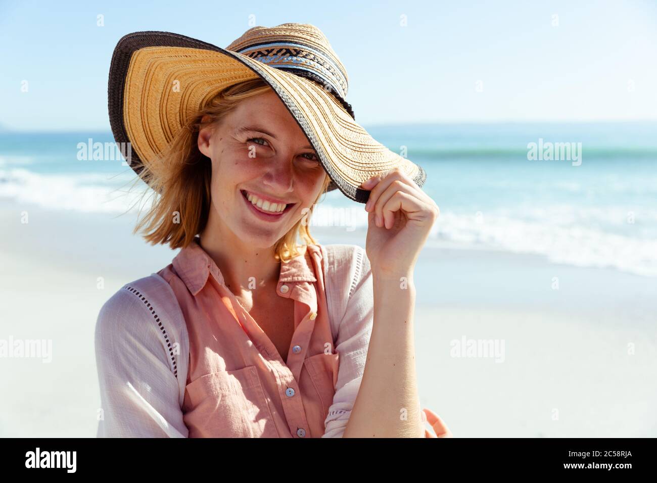 Portrait d'une femme portant un chapeau souriant sur la plage Banque D'Images