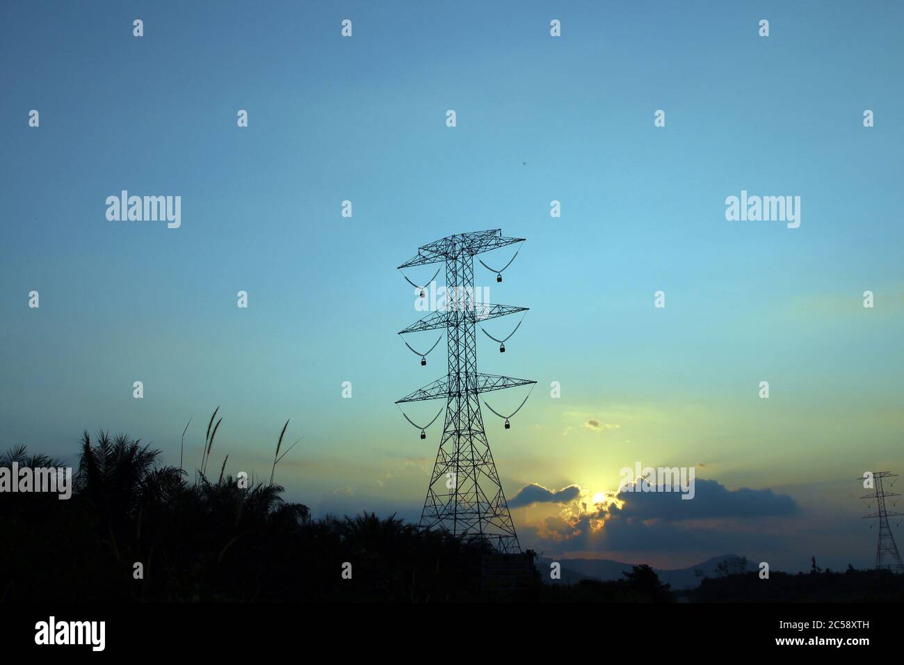 Résumé nature fond. Spectaculaire heure d'or ciel nuageux coucher de soleil avec rayons de soleil sur poteau électrique haute tension Banque D'Images