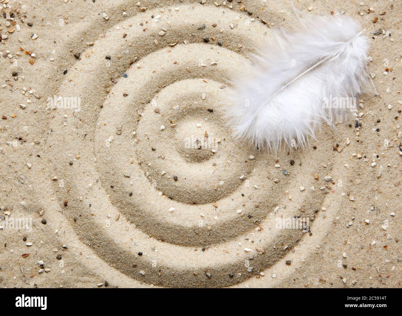 plume blanche sur cercles de sable Banque D'Images