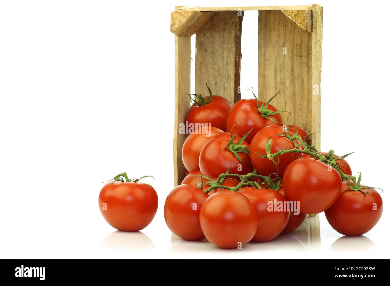 tomates fraîches sur la vigne dans une caisse en bois sur fond blanc Banque D'Images