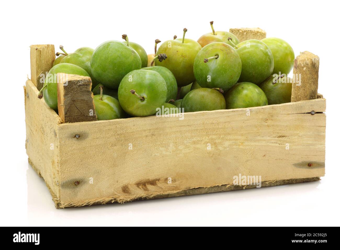 Prunes 'Reine Claude' fraîches dans une caisse en bois sur fond blanc Banque D'Images