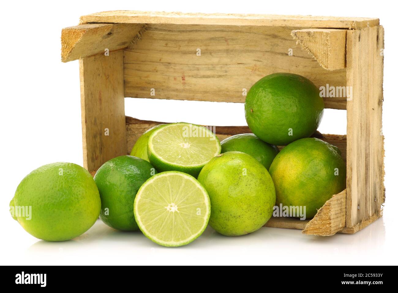 fruits frais de lime dans une caisse en bois sur fond blanc Banque D'Images