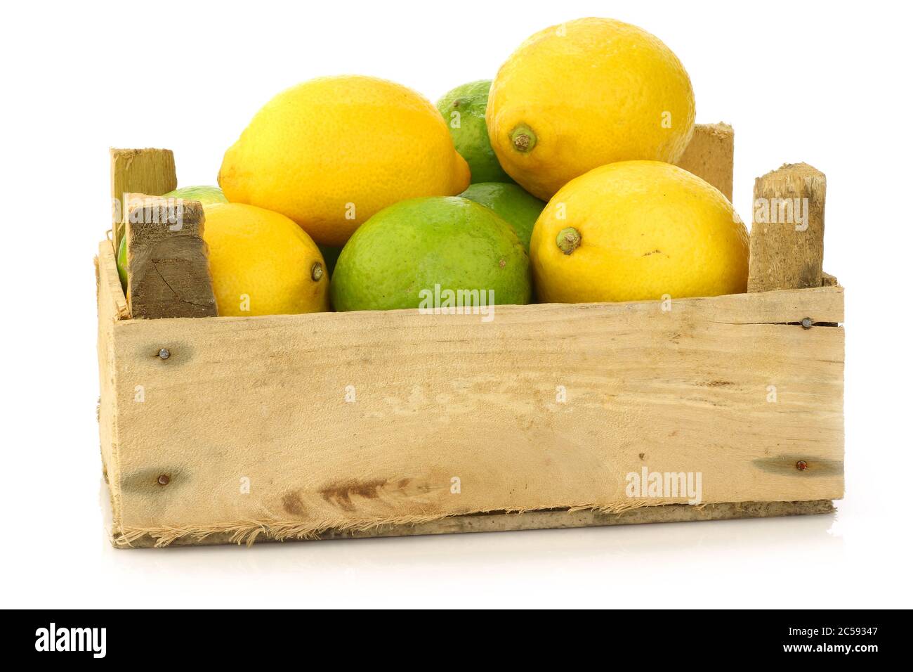 citrons frais et fruits au citron vert dans une boîte en bois sur fond blanc Banque D'Images