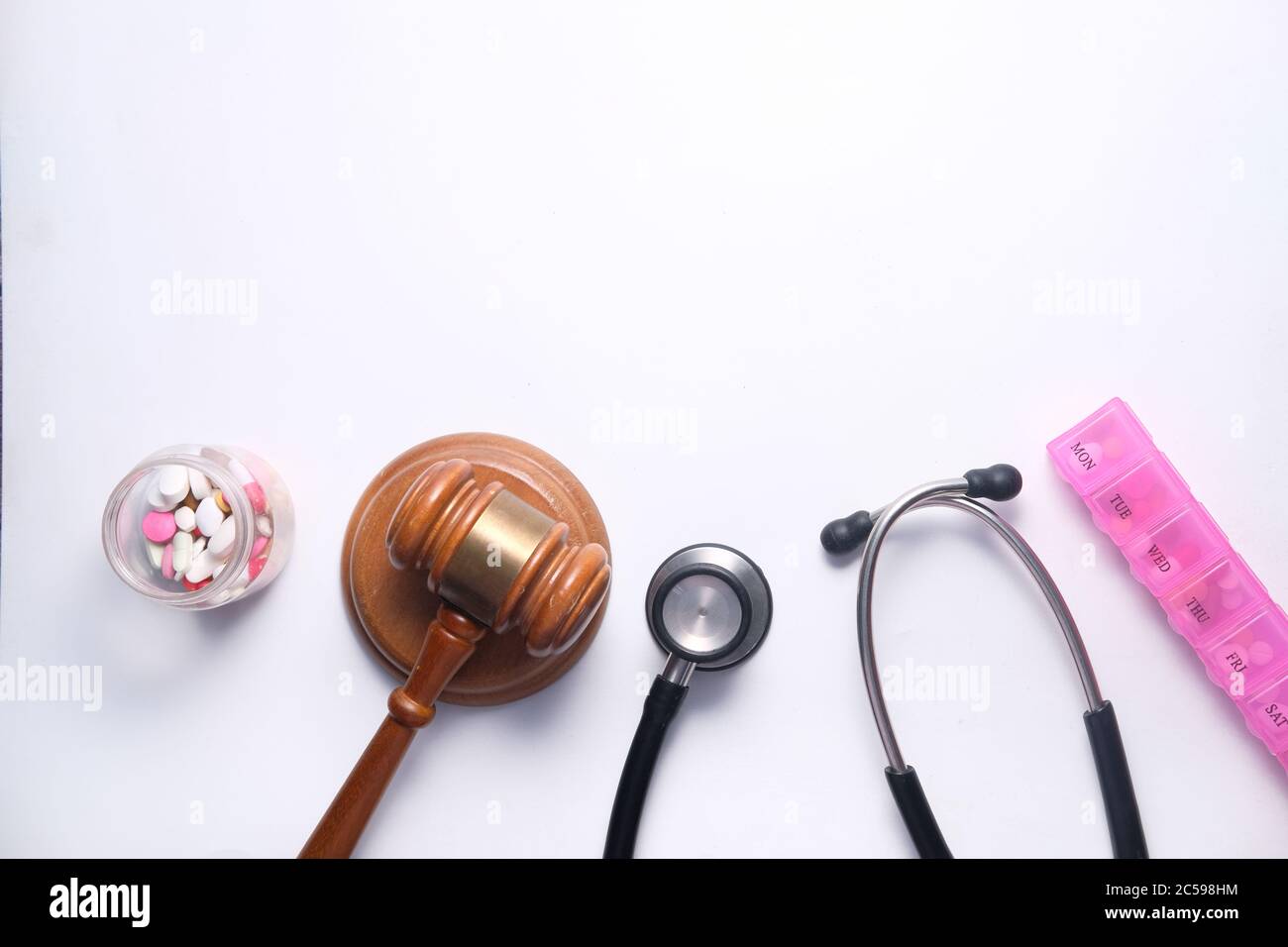 Vue de dessus du gavel, du stéthoscope et des pilules sur fond blanc Banque D'Images