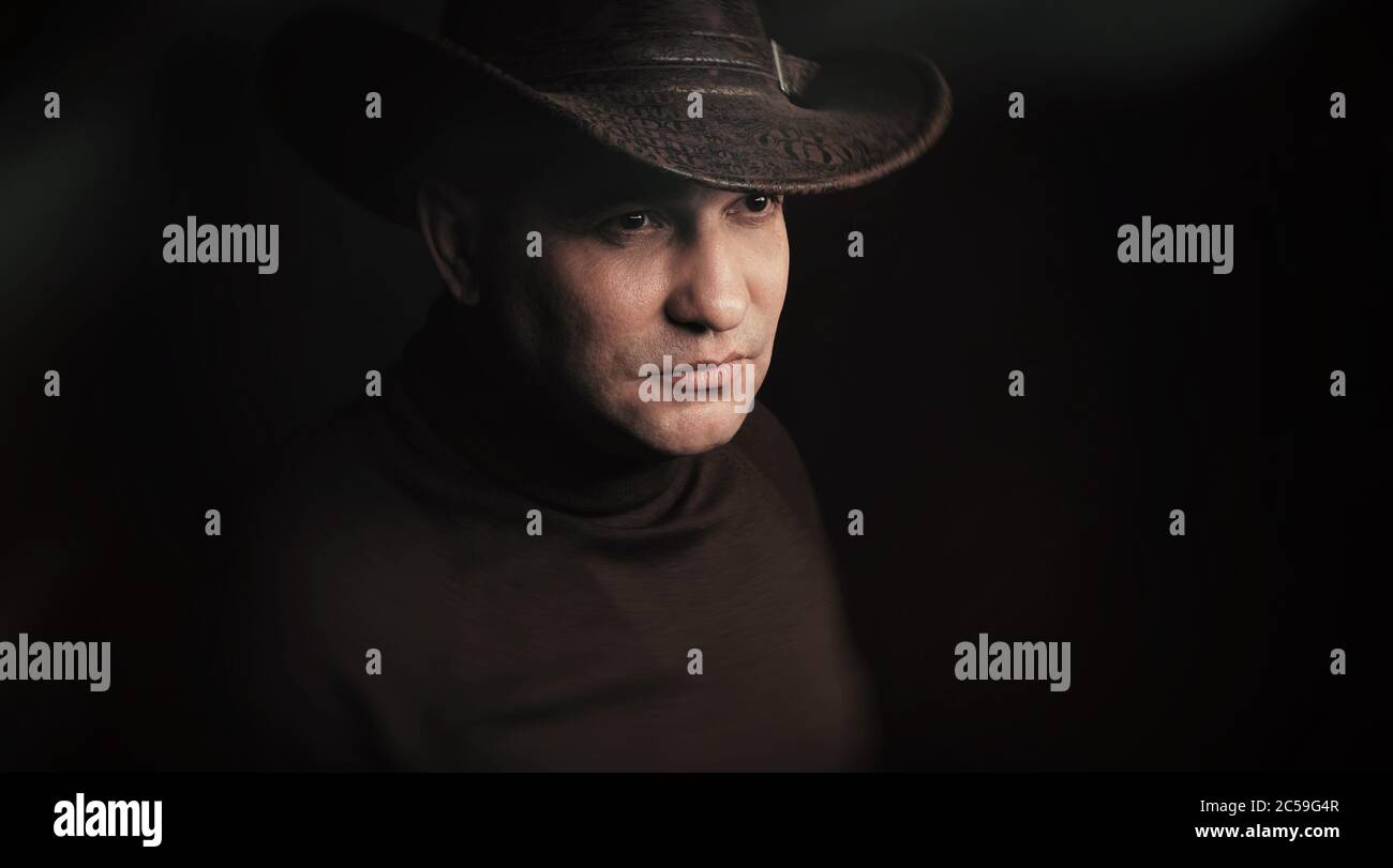 homme portant un chapeau de cow-boy sur fond noir de studio Banque D'Images