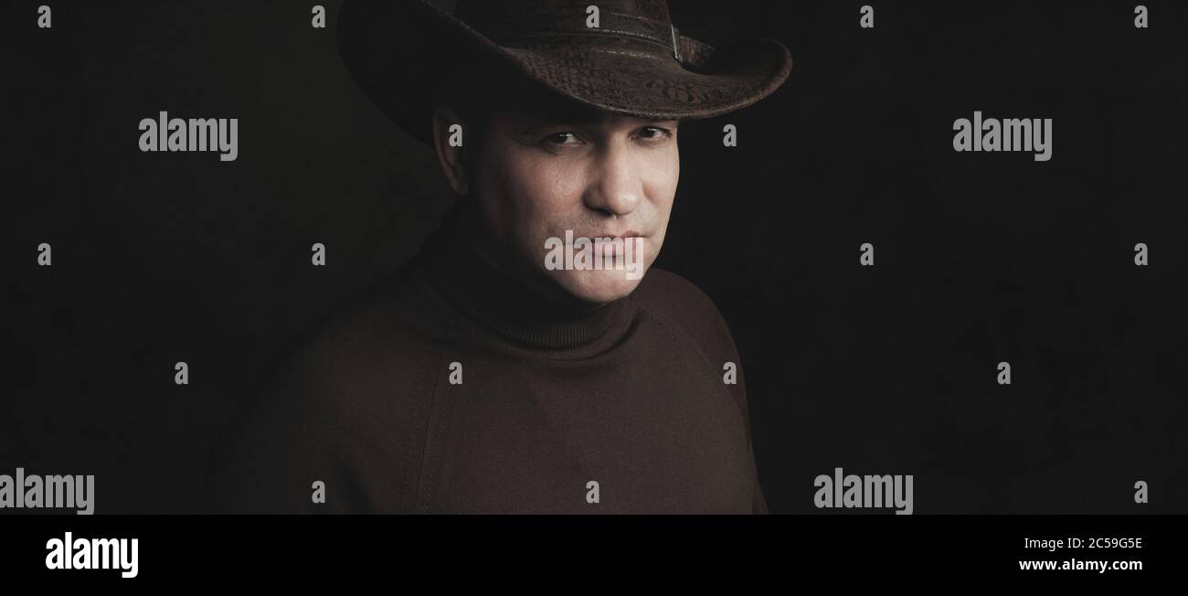 homme portant un chapeau de cow-boy sur fond noir de studio Banque D'Images