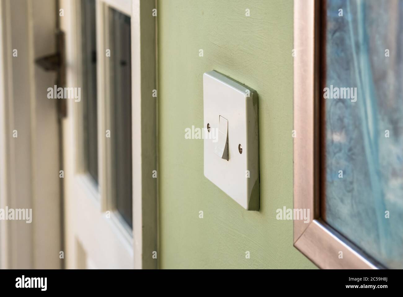 Image isolée d'un interrupteur d'éclairage intérieur en position d'arrêt.  Vue à côté d'une petite peinture murale et d'une porte intérieure en bois  menant à une pièce Photo Stock - Alamy