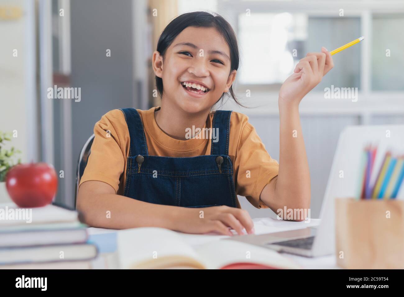 Bonne fille asiatique en ligne à la maison. Concept d'éducation et d'e-learning. Banque D'Images