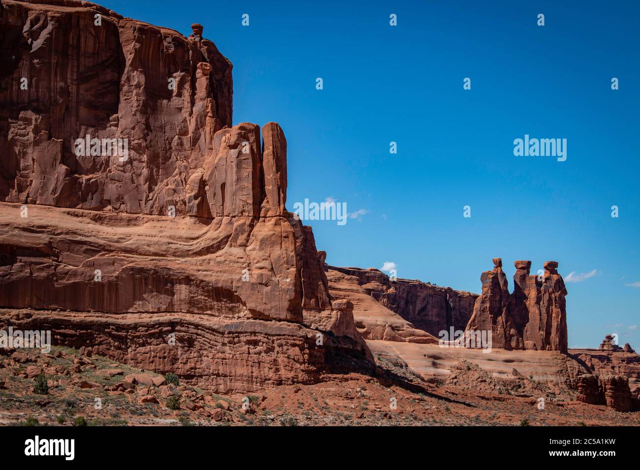 Trois gossips se posent à la base d'énormes falaises de roche rouge dans le parc national d'Arches, à l'extérieur de Moab, Utah Banque D'Images