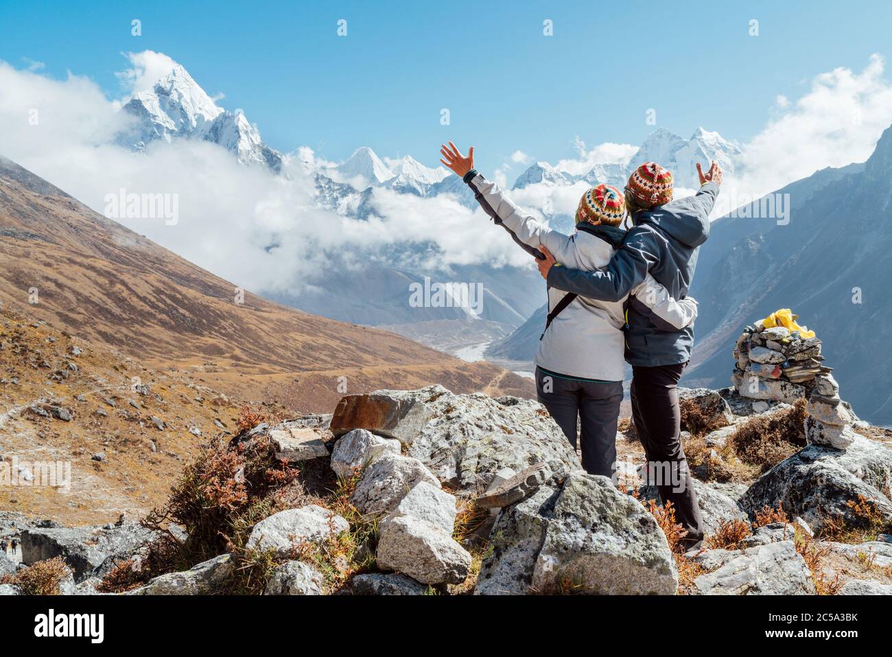 Couple en hausse d'armes se réjouissant de l'Everest base Camp randonnée route près de Dughla 4620m. Backpackers a laissé des sacs à dos et des bâtons de randonnée et appréciant la vallée vie Banque D'Images