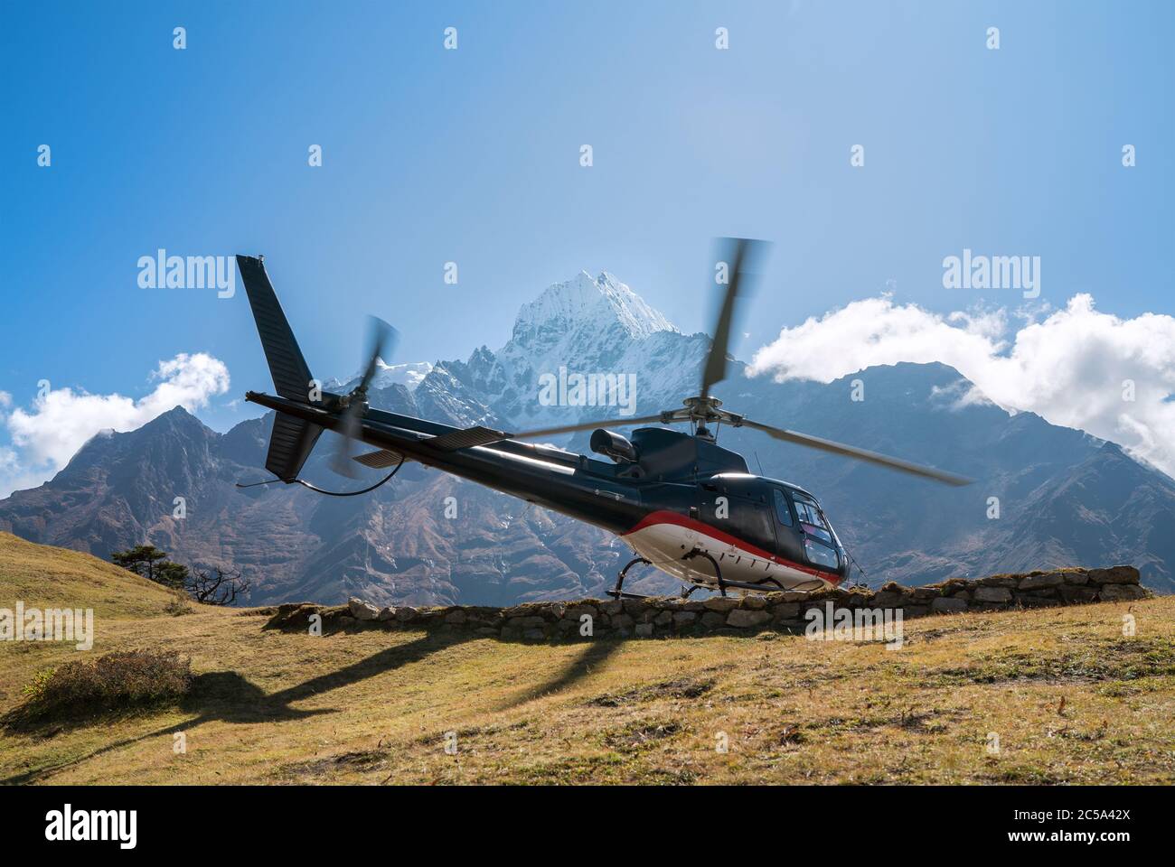 Atterrissage en hélicoptère civil dans les montagnes de l'Himalaya en haute altitude. Image de concept de sécurité, transport aérien et assurance voyage. Banque D'Images