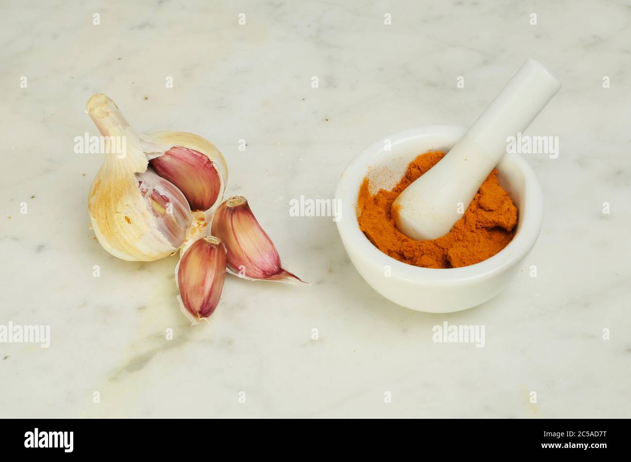 Bulbe d'ail et clous de girofle avec curcuma dans un pilon et mortier sur marbre Banque D'Images