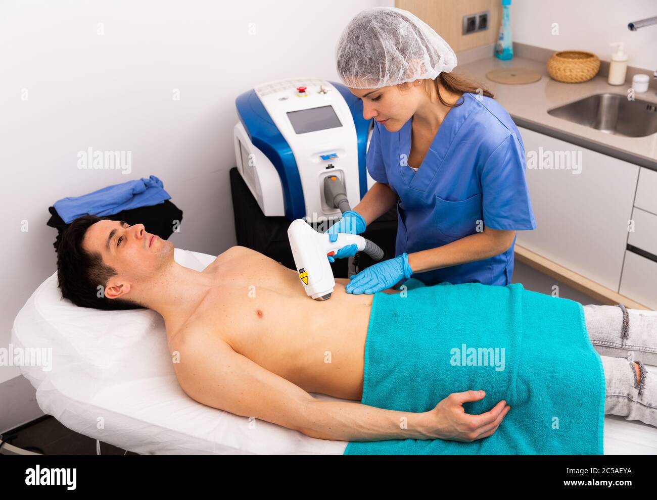 Jeune client masculin recevant un traitement matériel d'épilation sur le  thorax par un cosmetologue professionnel en clinique esthétique Photo Stock  - Alamy
