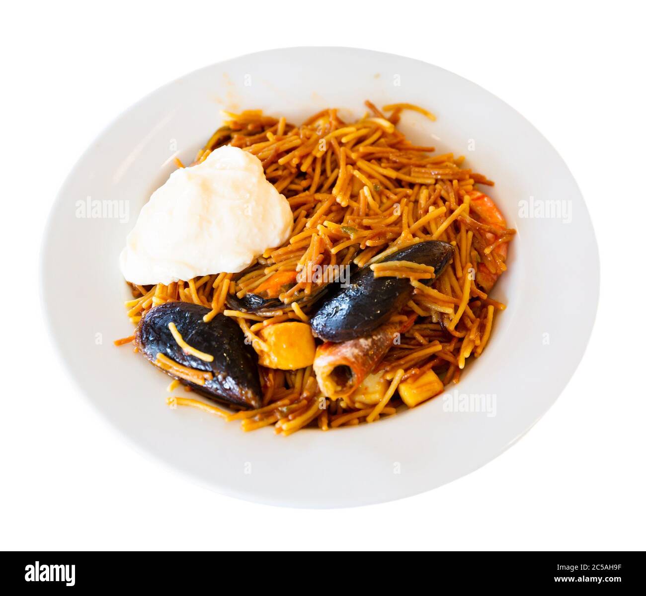 Paella fraîchement préparée avec des pâtes fideua et des fruits de mer variés servis sur une assiette blanche. Isolé sur fond blanc Banque D'Images