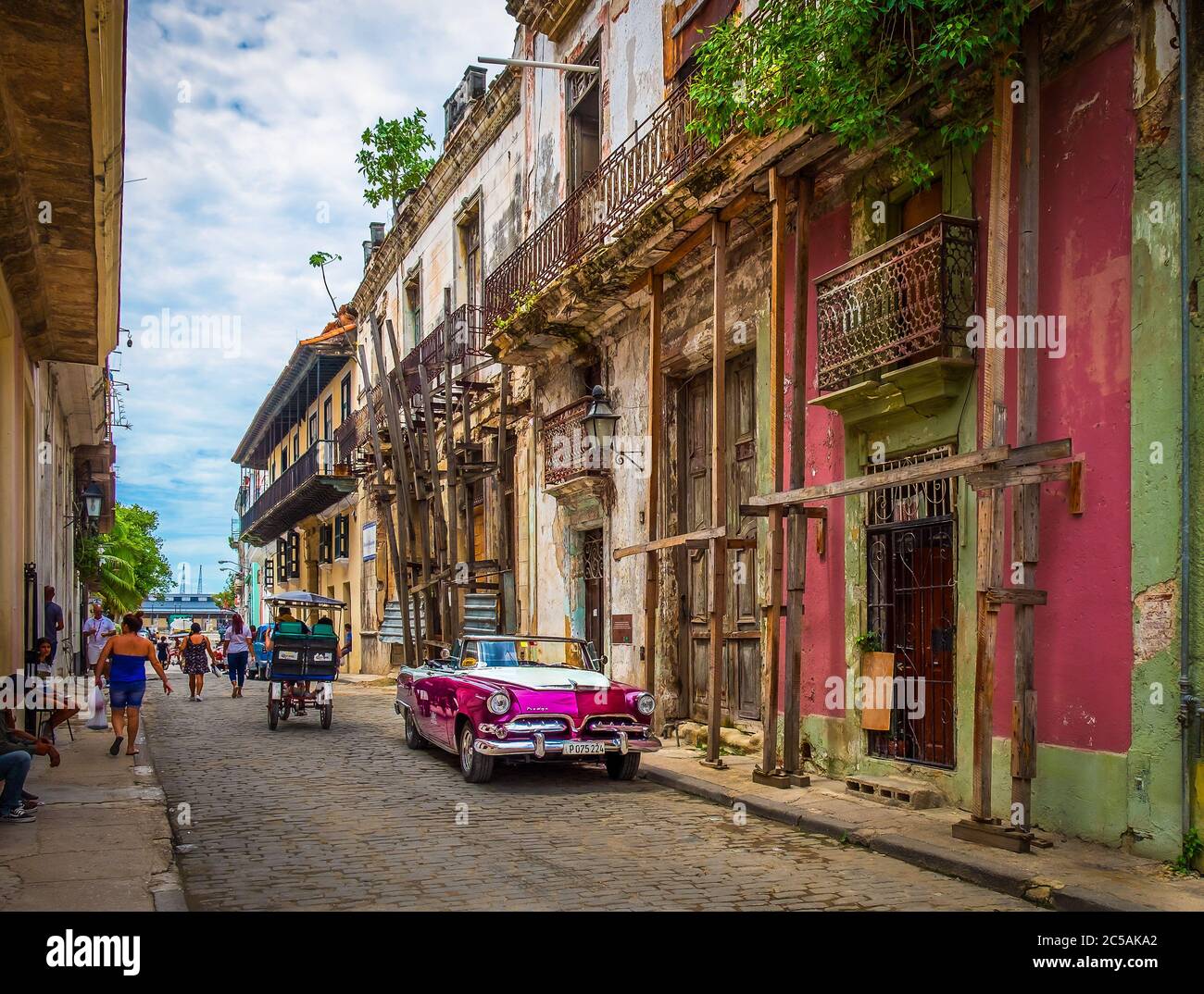 La Havane, Cuba, juillet 2019, scène urbaine avec une voiture Dodge de location pourpre des années 50 garée dans la rue dans la partie la plus ancienne de la ville Banque D'Images