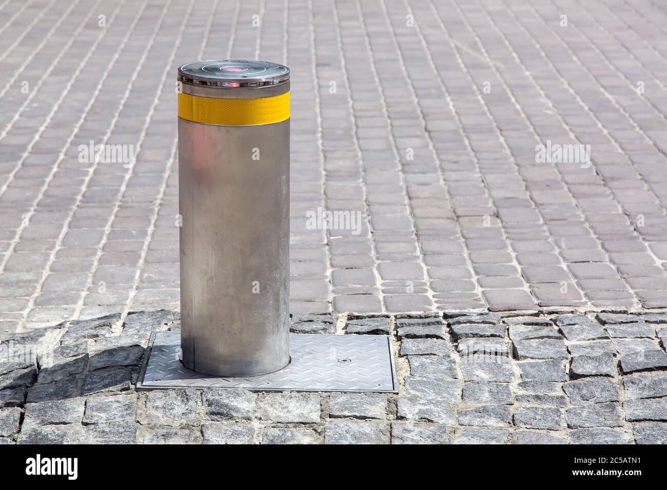borne électrique gris hydraulique avec bande réfléchissante jaune sur l'ancienne route en pierre, vue latérale avec espace pour copier. Banque D'Images