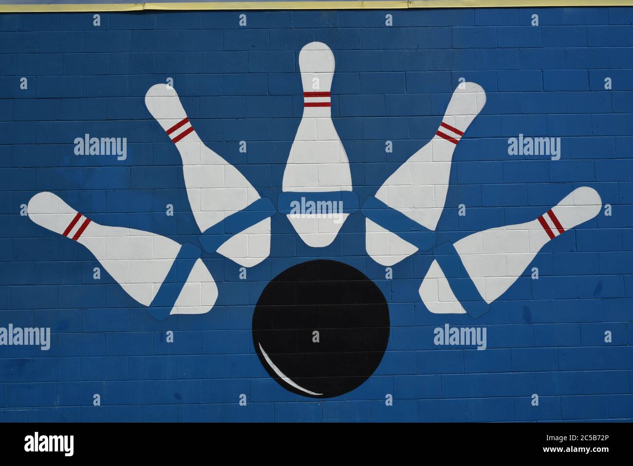 Un dessin de cinq quilles et une boule de bowling sur un mur de ciment peint en bleu dans une allée de bowling en Colombie-Britannique, Canada. Banque D'Images