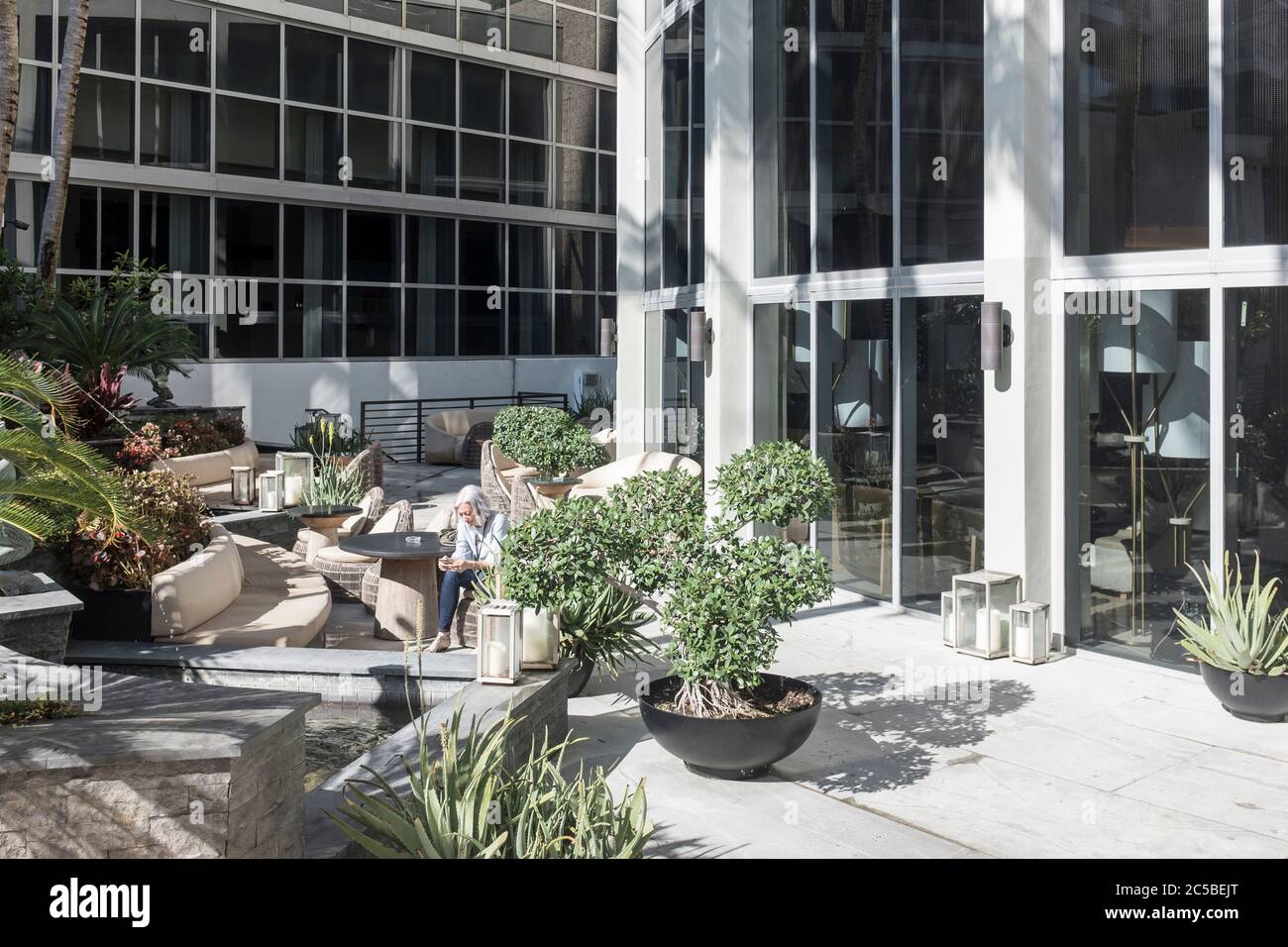 Une femme est baignée de lumière du soleil dans un coin salon extérieur de l'hôtel Nobu à l'Eden Roc à Miami Beach, Floride, États-Unis Banque D'Images