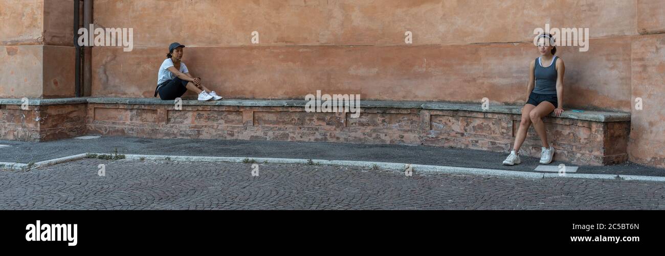 Mère et fille assis sur un banc de briques devant un beau mur en terracota à Bologne Italie Banque D'Images