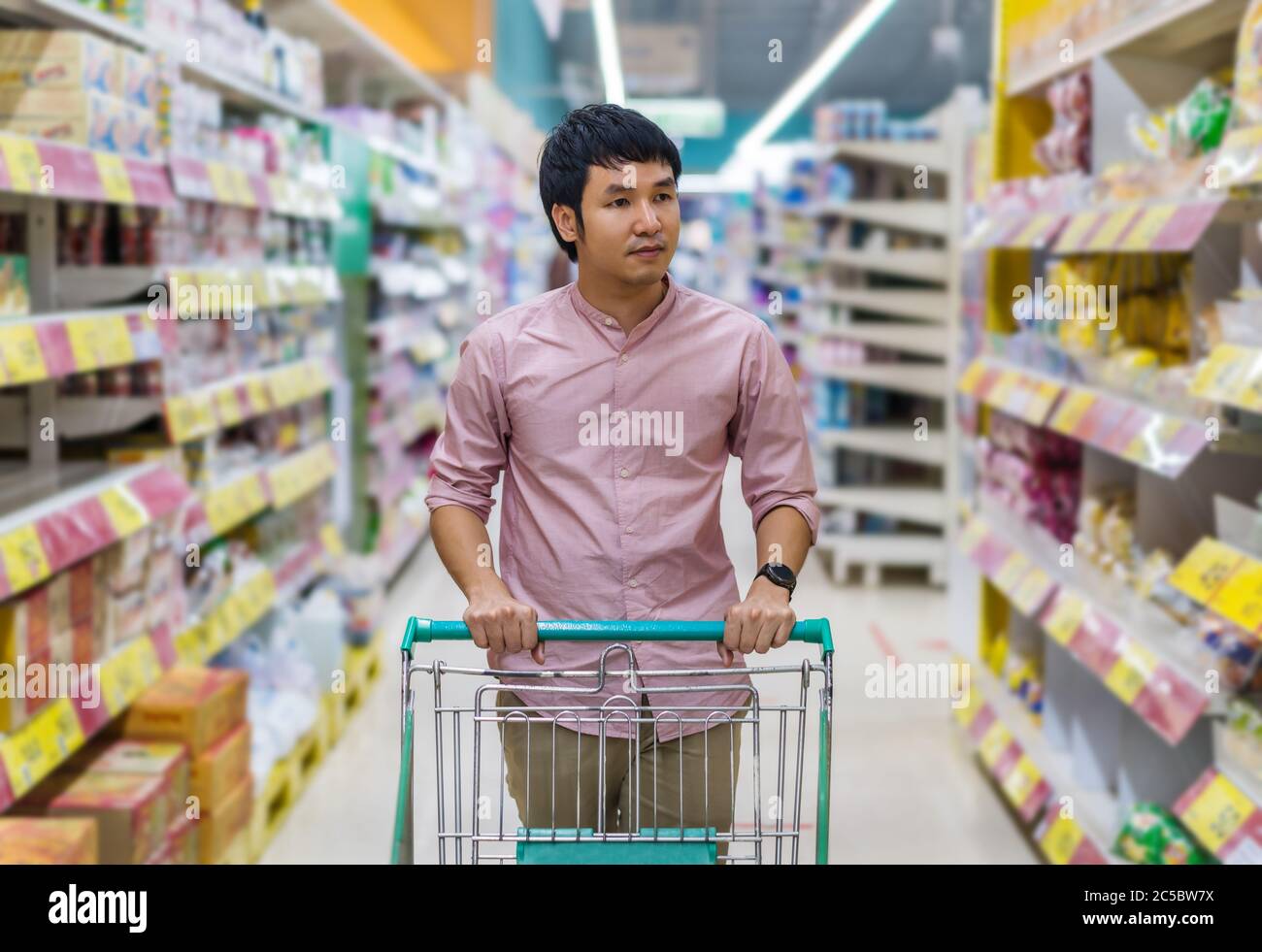 jeune homme asiatique avec un chariot dans un grand magasin de supermarché Banque D'Images