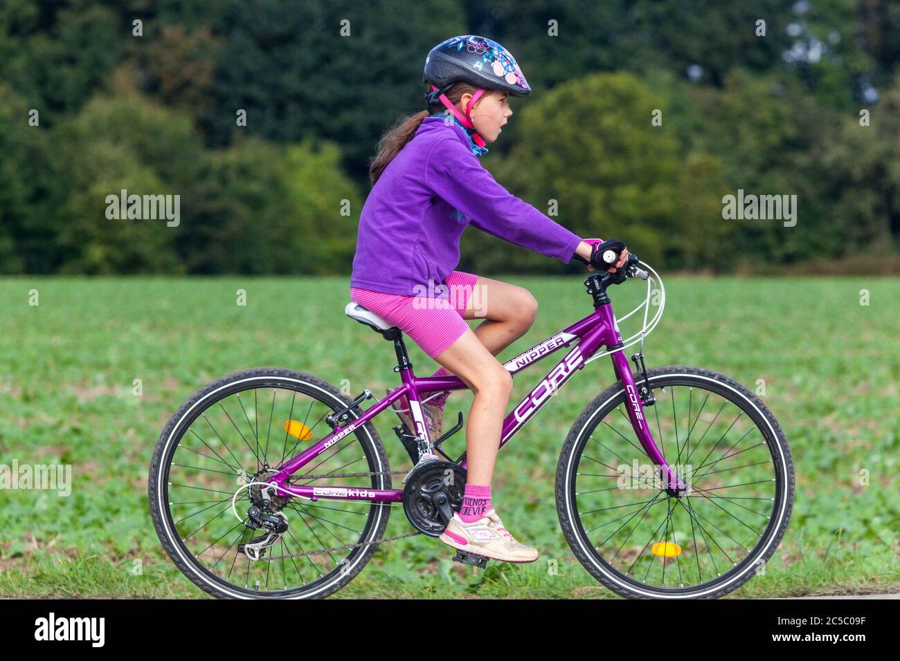 Enfant sur une piste cyclable, fille à bord d'un casque de vélo, enfant à vélo avec casque Banque D'Images