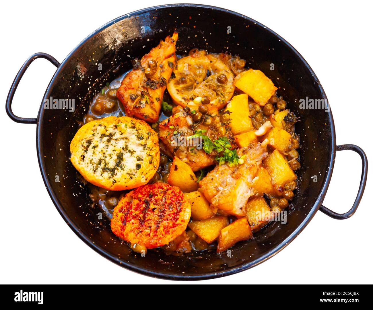 Délicieux monkfish rôti au citron, aux pommes de terre et aux petits pois verts servis dans une poêle à repasser avec du pain grillé. Isolé sur fond blanc Banque D'Images