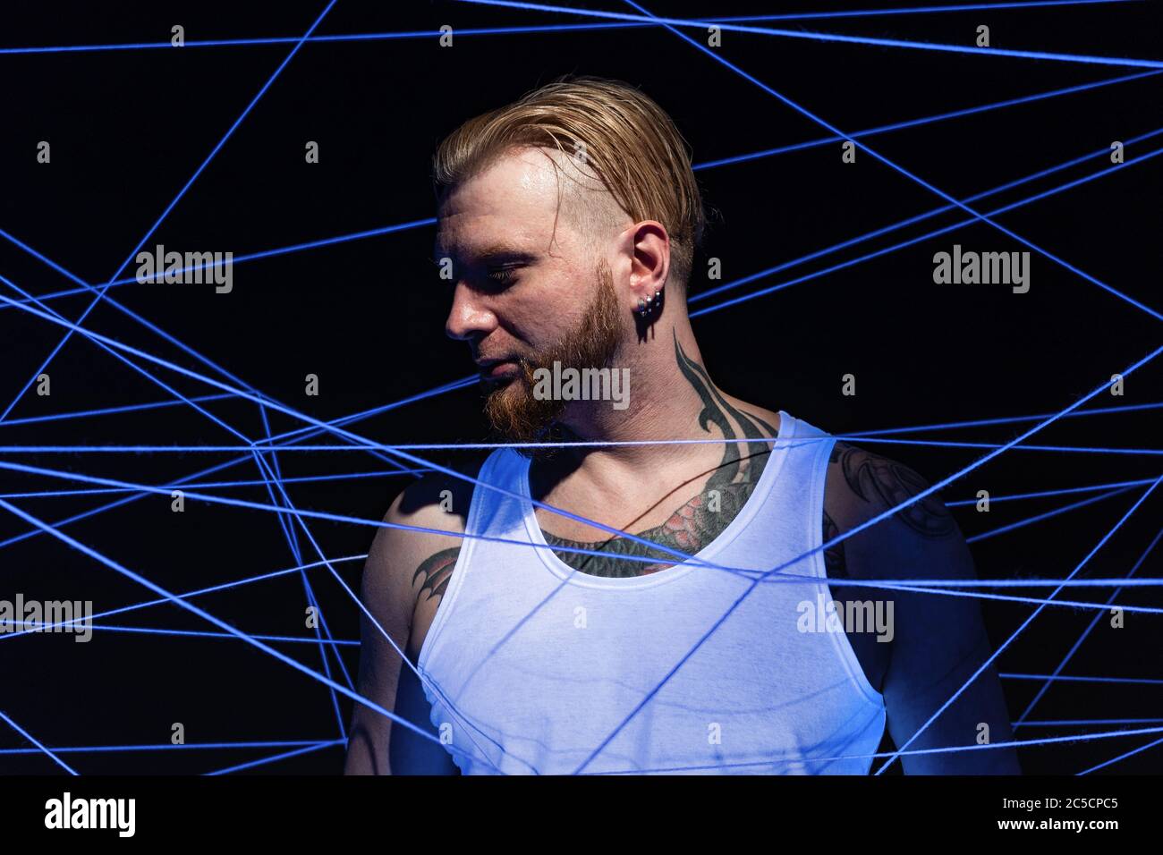 Homme tatoué emmêlé dans des fils de lumière néon Banque D'Images