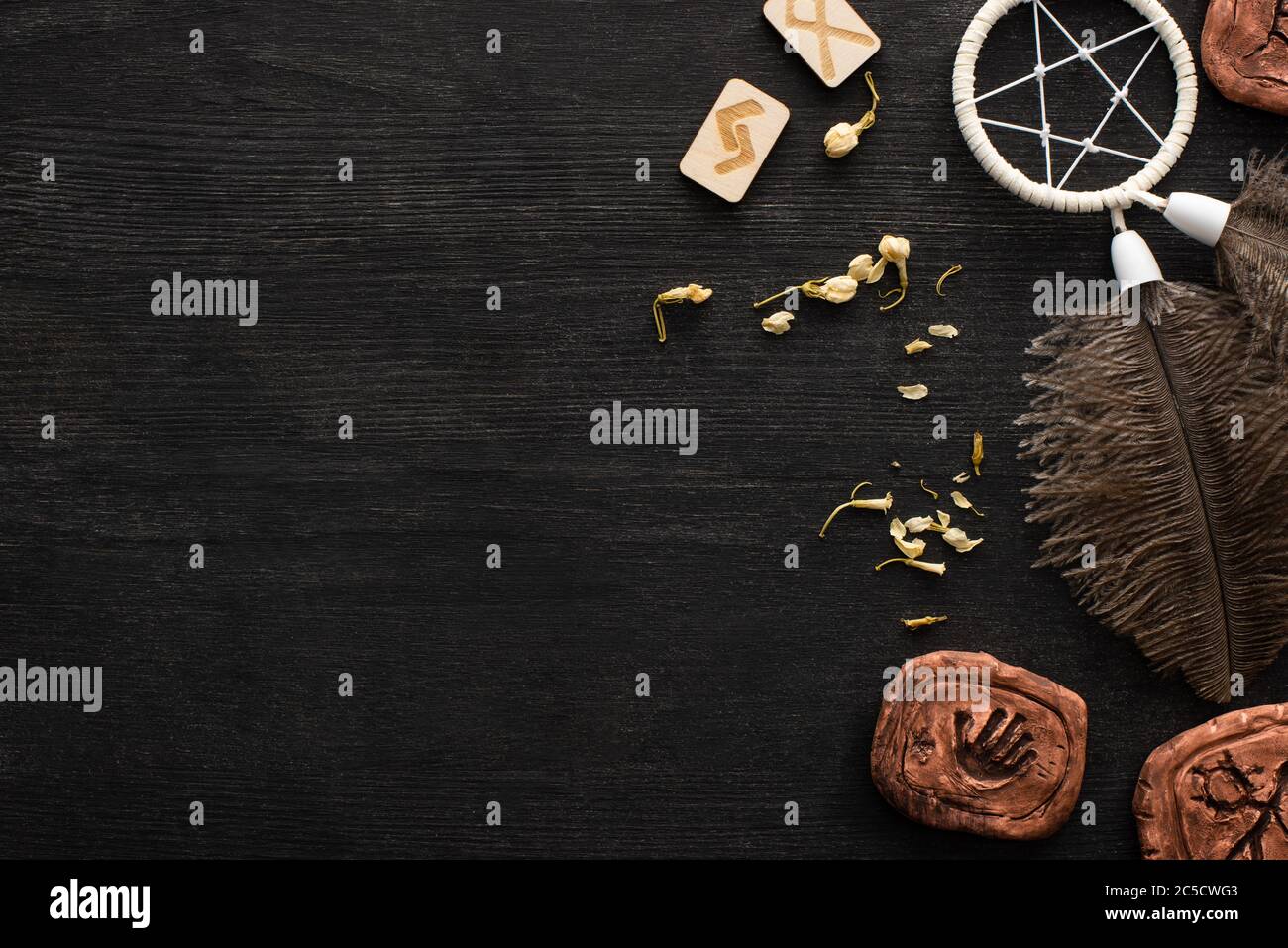 Vue de dessus de dreamcatcher, runes et fleurs sèches sur fond en bois noir avec espace de copie Banque D'Images