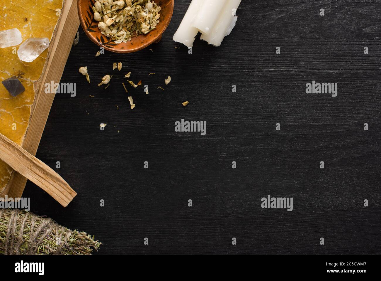 Vue de dessus du livre, bougies avec bâton de tache et cristaux sur fond de bois sombre Banque D'Images