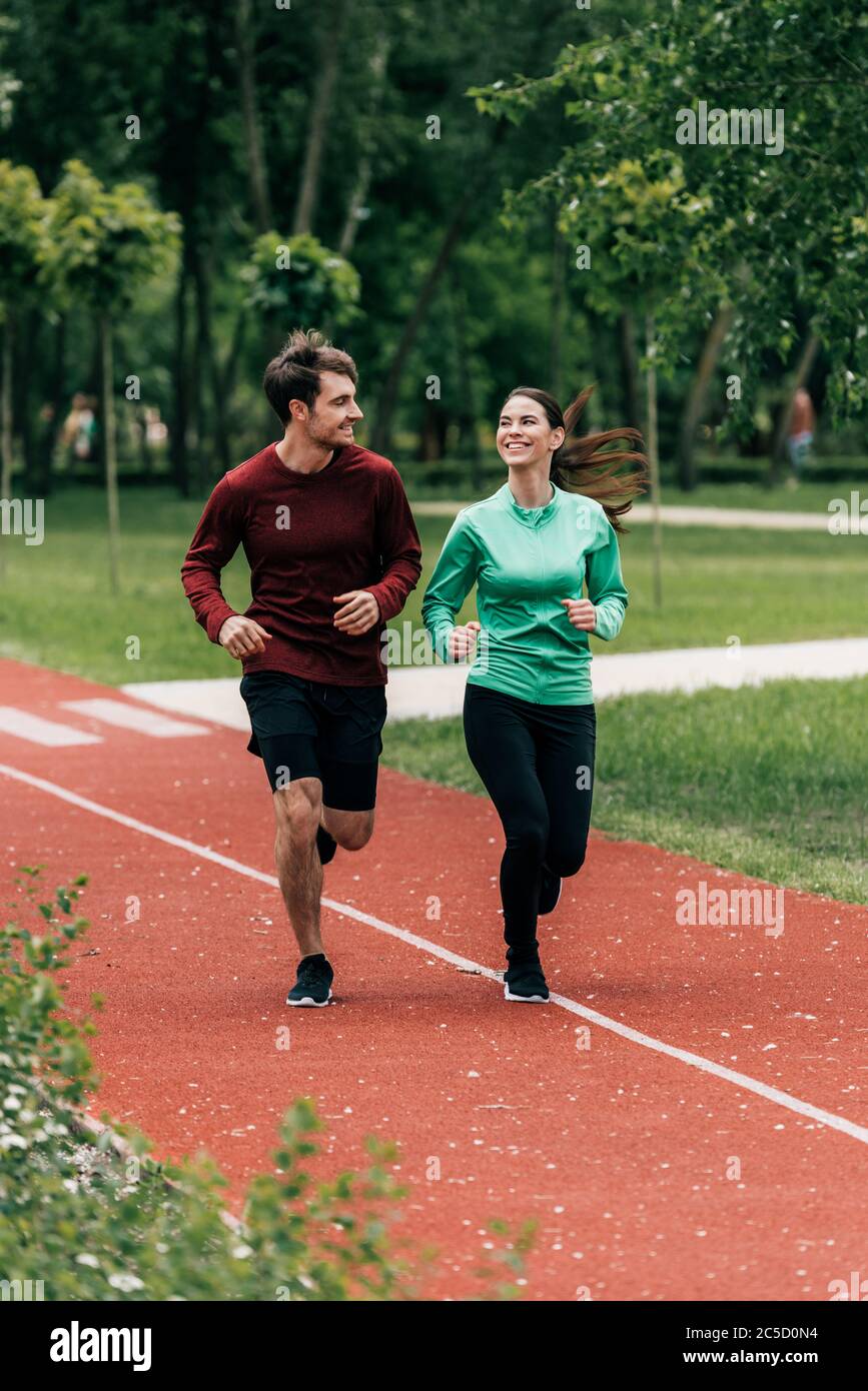 Objectif sélectif de sportswoman souriant au petit ami pendant le jogging dans le parc Banque D'Images