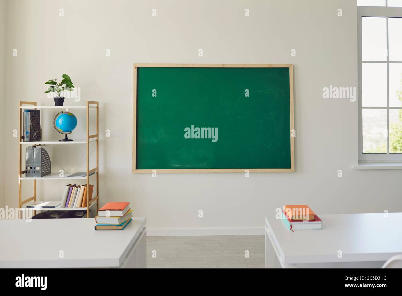 Intérieur blanc de la salle de classe. Salle de bains lumineuse avec fenêtres, table, chaise, planche verte Banque D'Images