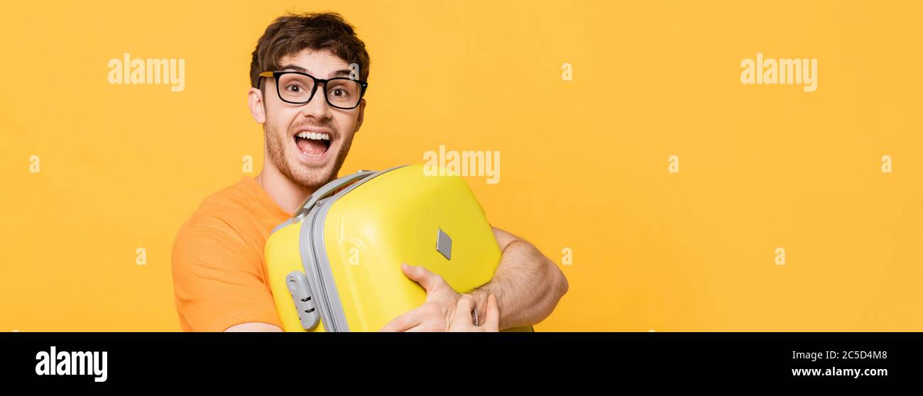 gai mâle touriste tenue valise pour vacances d'été sur jaune, en-tête de site web Banque D'Images
