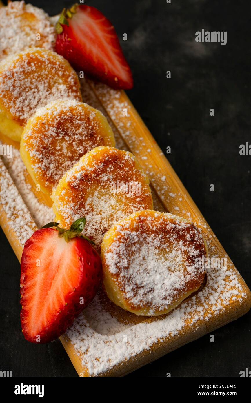 fritter caillé, cheesecakes sucrées sur fond sombre, avec baies de fraises, service de restaurant Banque D'Images