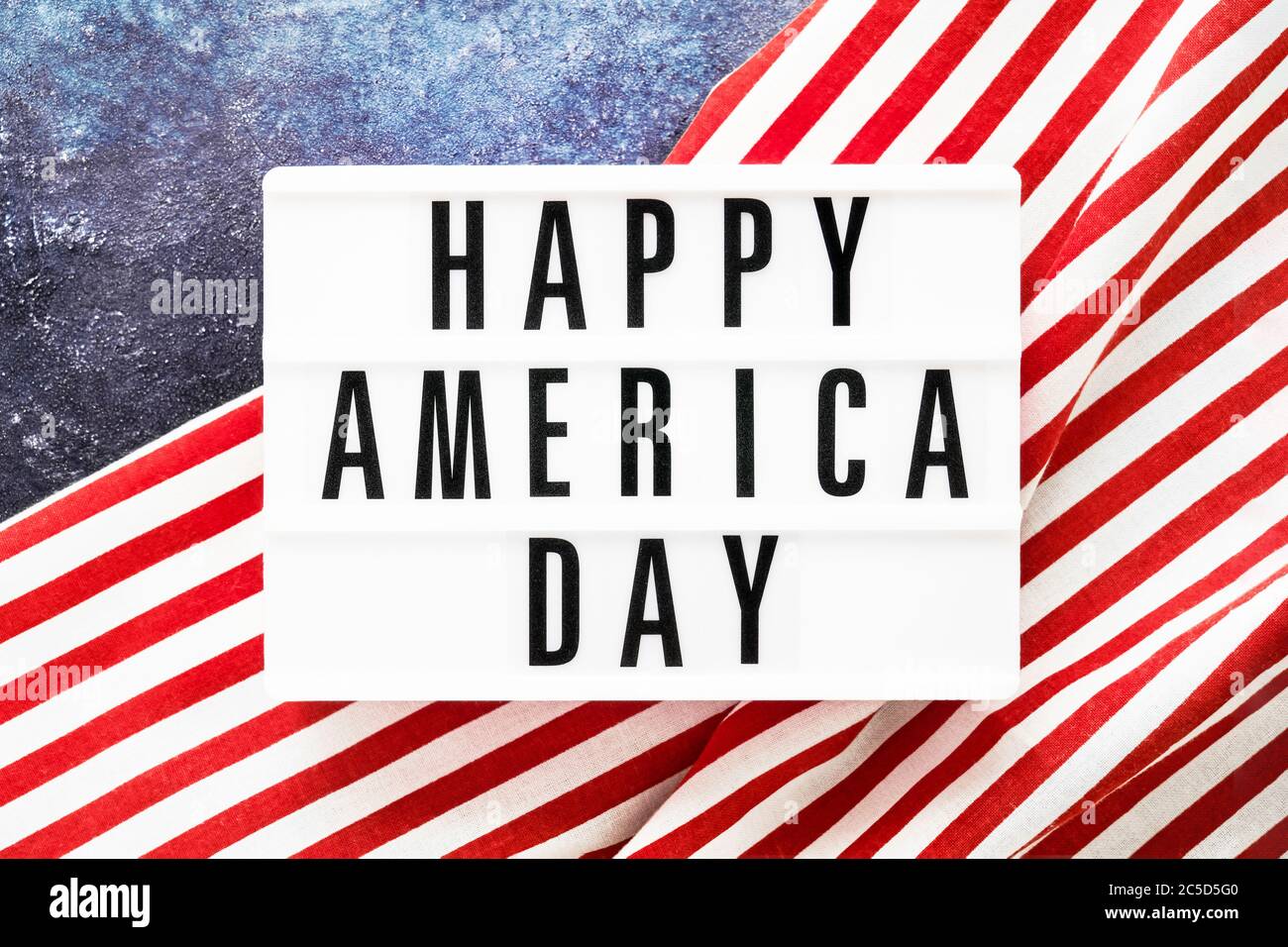 HAPPY AMERICA DAY écrit dans une boîte lumineuse sur fond rouge-bleu. Vue de dessus, espace de copie. Concept de jour d'indépendance Banque D'Images