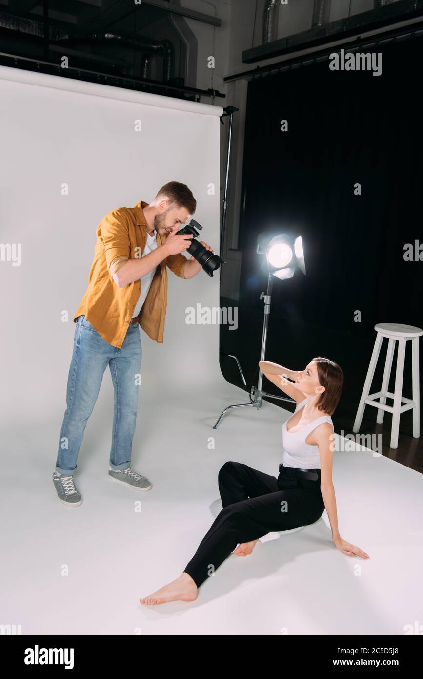 Vue latérale du photographe travaillant avec un magnifique modèle au sol dans un studio photo Banque D'Images