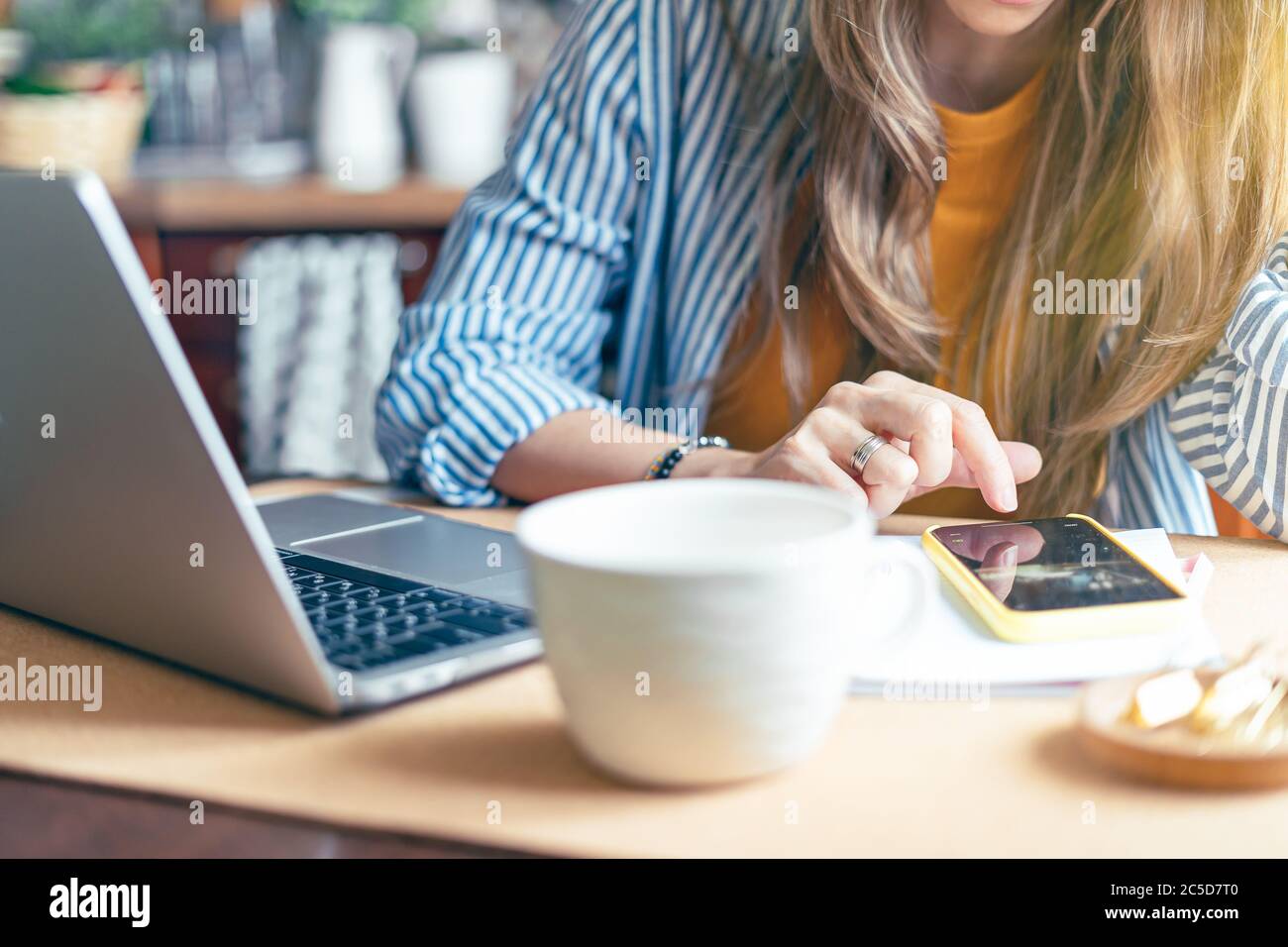 Femme d'affaires écran tactile et SMS sur smartphone. Fille travaillant à la maison kithcen bureau et de boire du café. Utilisation de l'ordinateur et du téléphone portable. Distance Banque D'Images